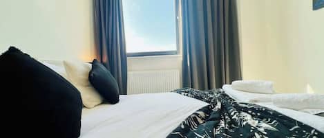 Une chambre d’hôtel avec un lit, une fenêtre avec des rideaux et un radiateur.