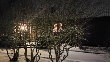A snow-covered outdoor area with bare trees and a building in the background.