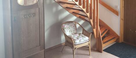 A wooden staircase with a wooden cabinet and a wicker chair in a room with a carpeted floor.