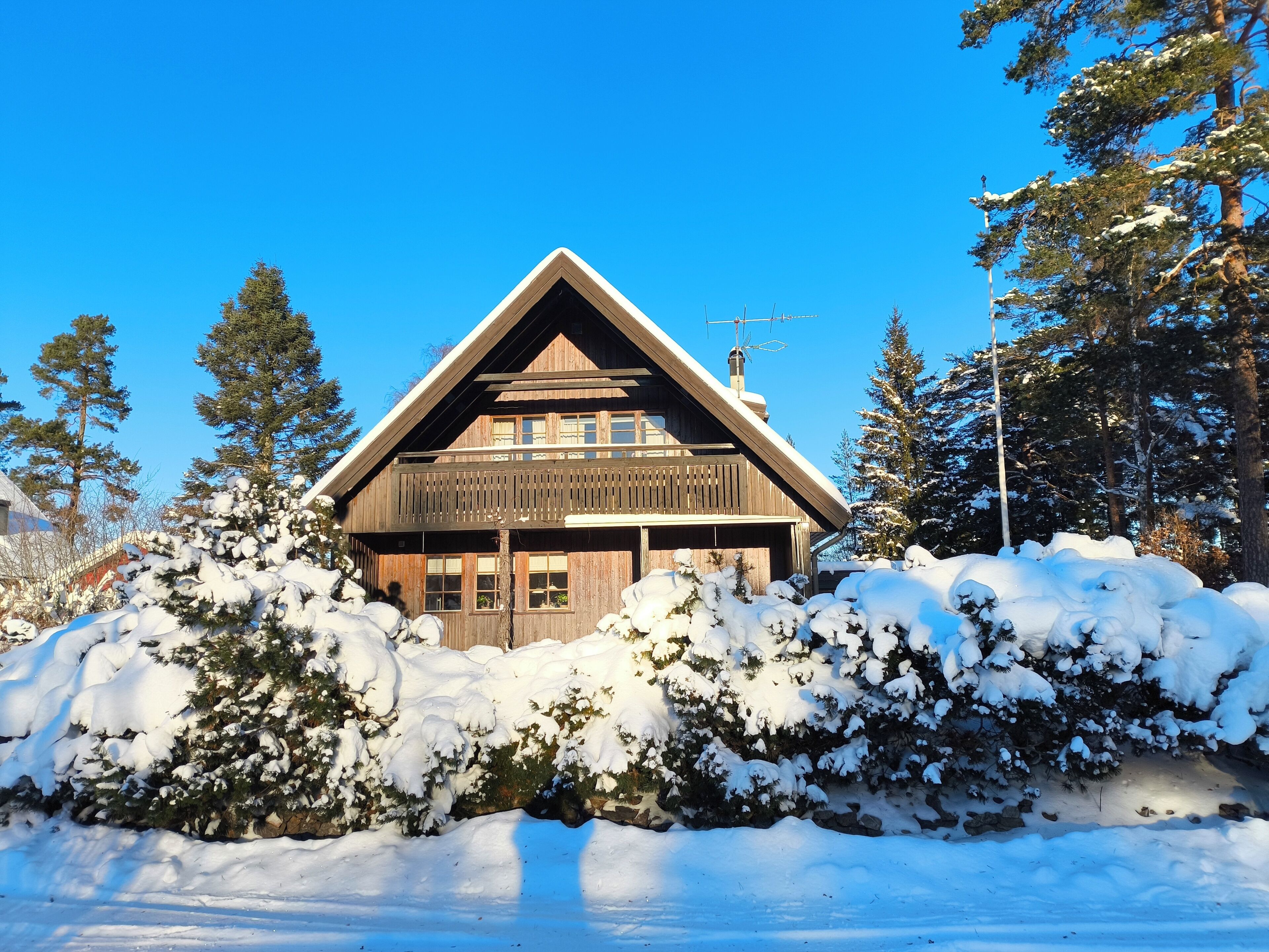 A wooden cabin with a gabled roof, surrounded by snow-covered trees.