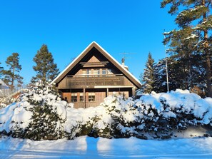 Una cabana de fusta amb teulat a dos vessants, envoltada d'arbres coberts de neu.