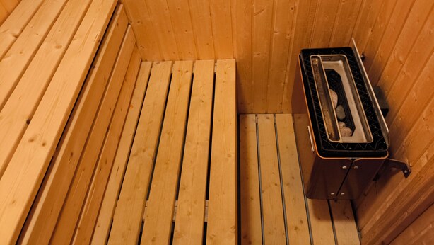 A sauna room with wooden benches and a metal bench.