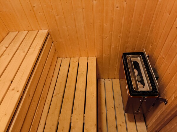 Un sauna avec des bancs en bois et un banc en métal.