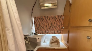 Ein kleines Badezimmer mit Dusche, Handtuchhalter und Toilette.