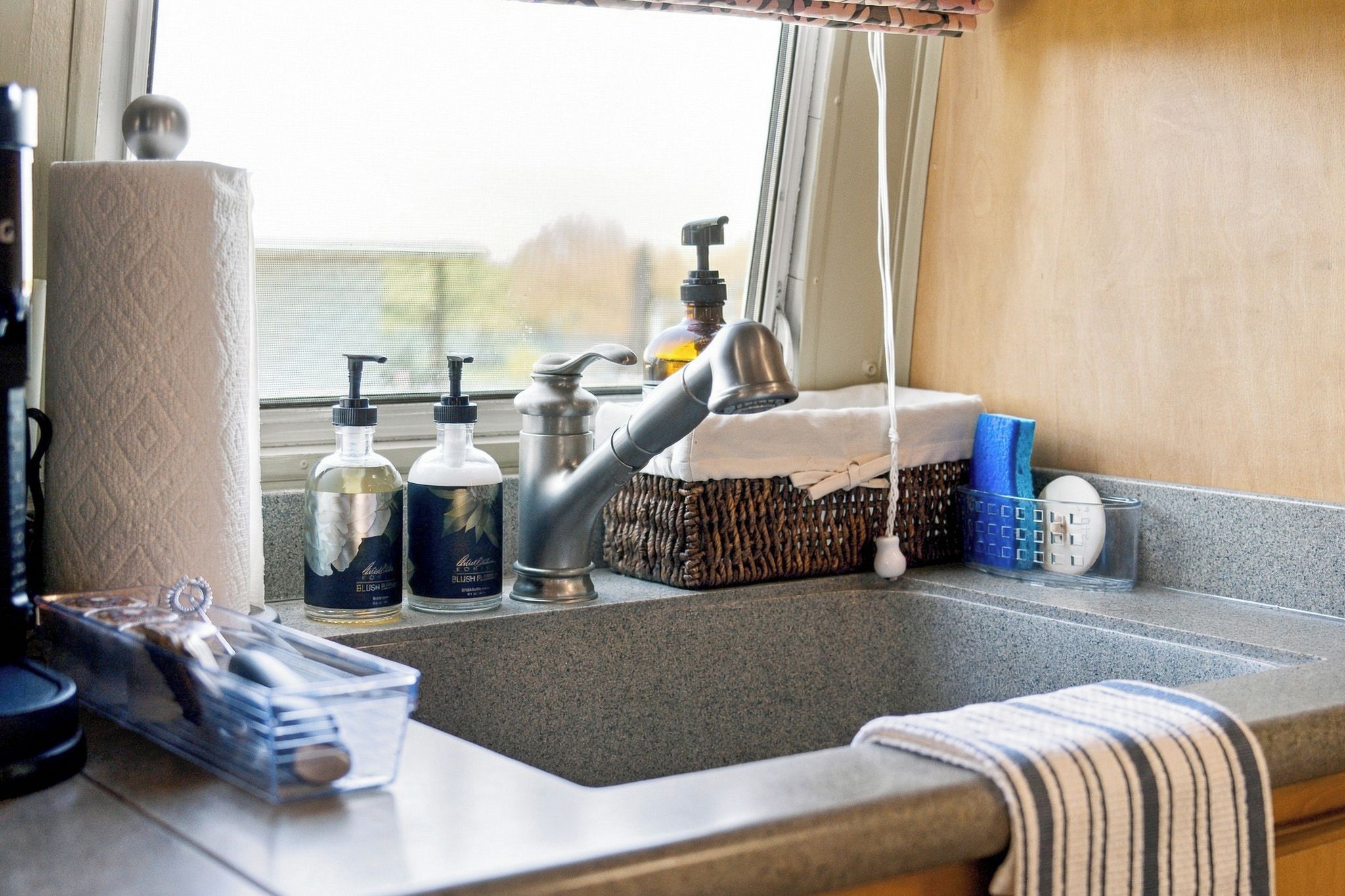 A kitchen sink with a faucet, a soap dispenser, and a bottle of liquid soap.