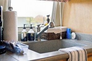 A kitchen sink with a faucet, a soap dispenser, and a bottle of liquid soap.