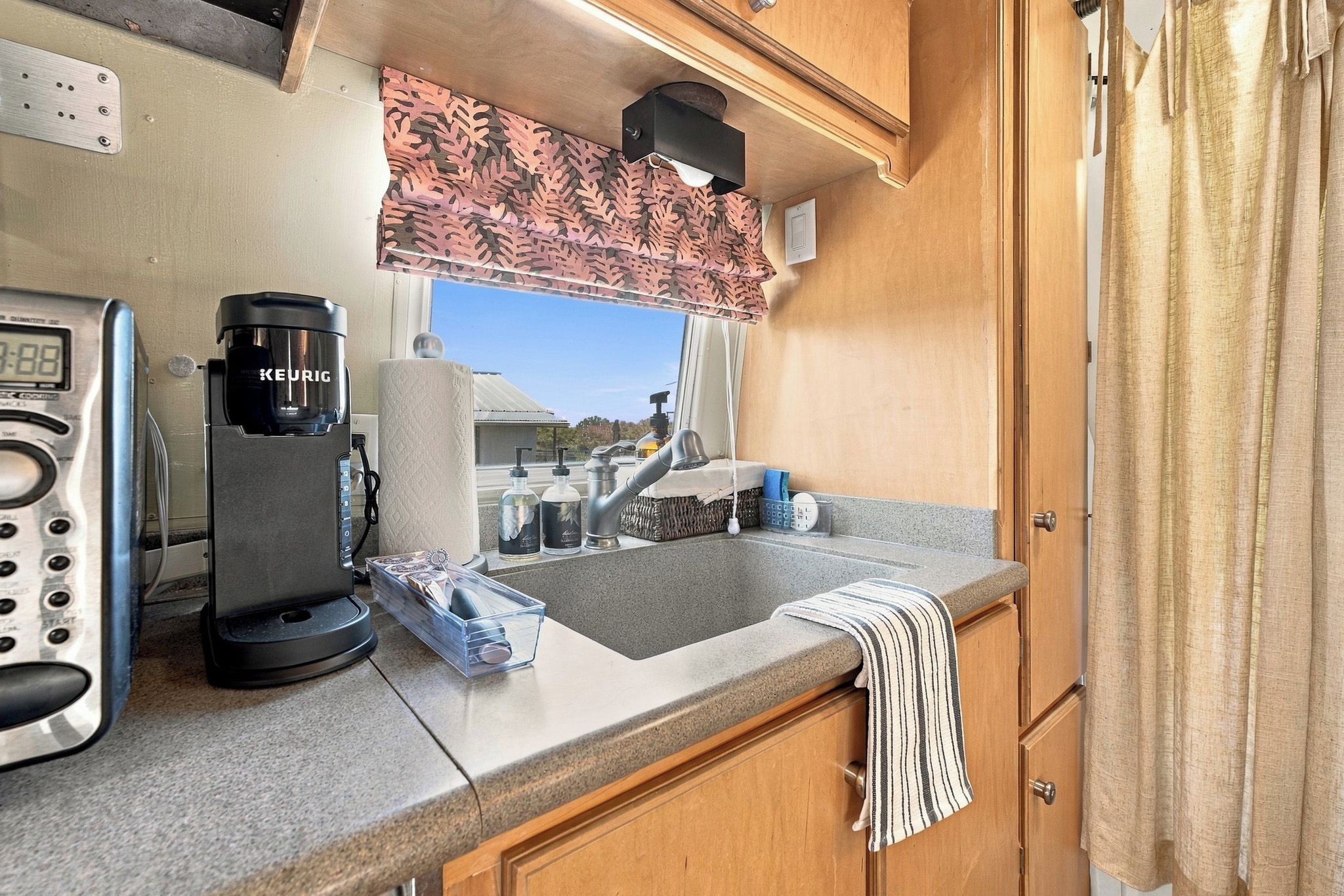 A kitchenette with a Keurig coffee maker, a sink, and a window with a view of the outdoors.