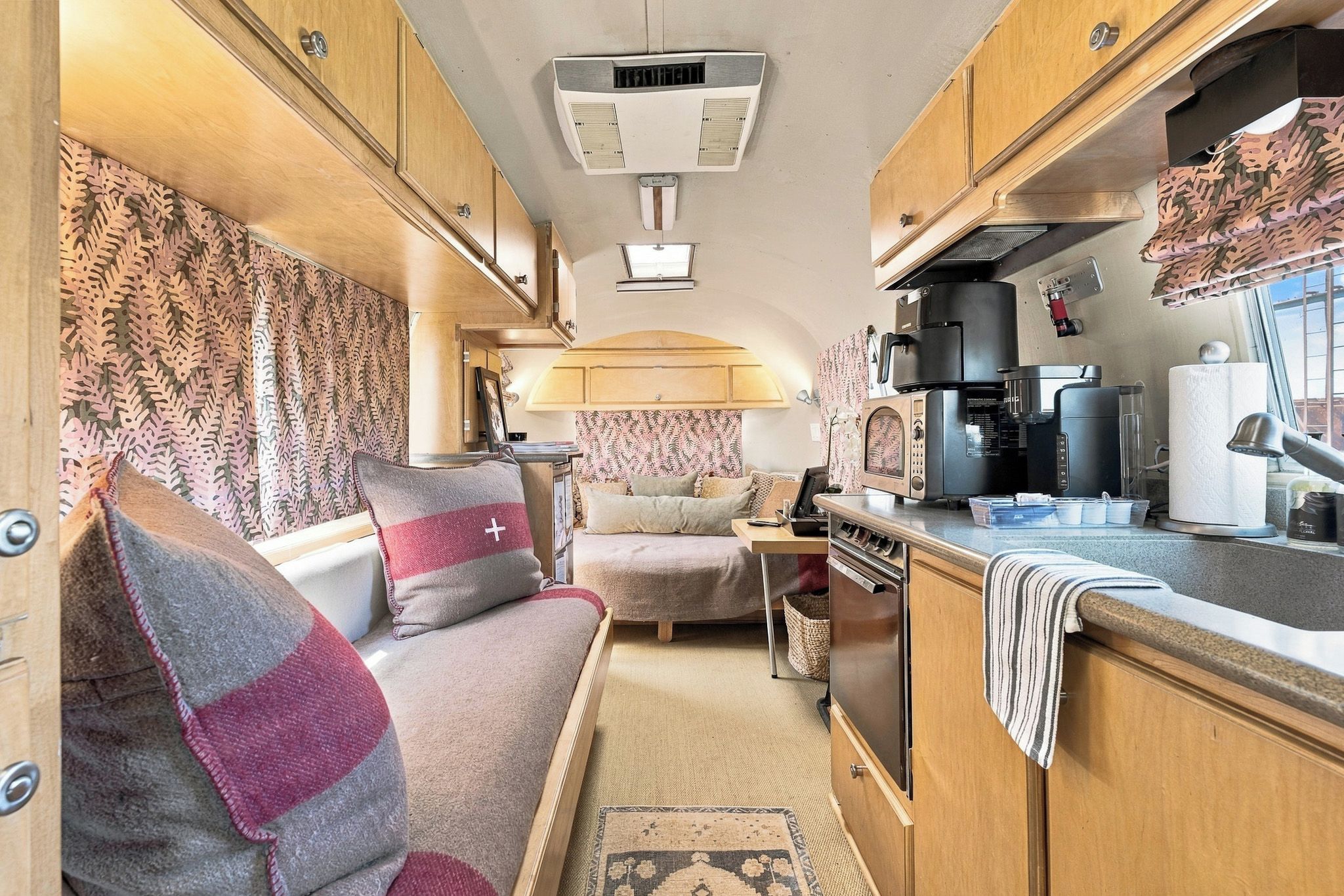 A compact RV interior with a kitchenette, a sofa, and a small table.