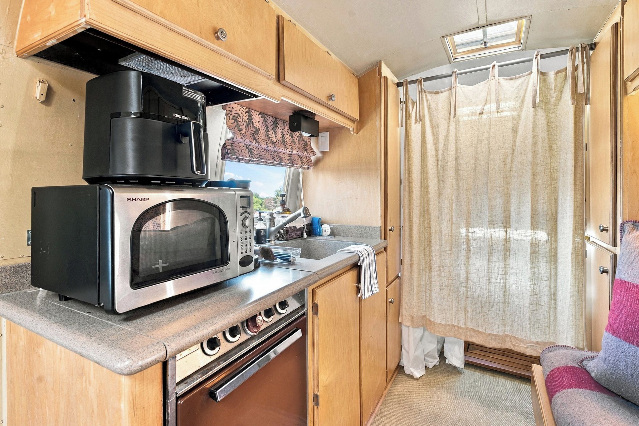 Una kitchenette pequeña con microondas, estufa y lavaplatos.