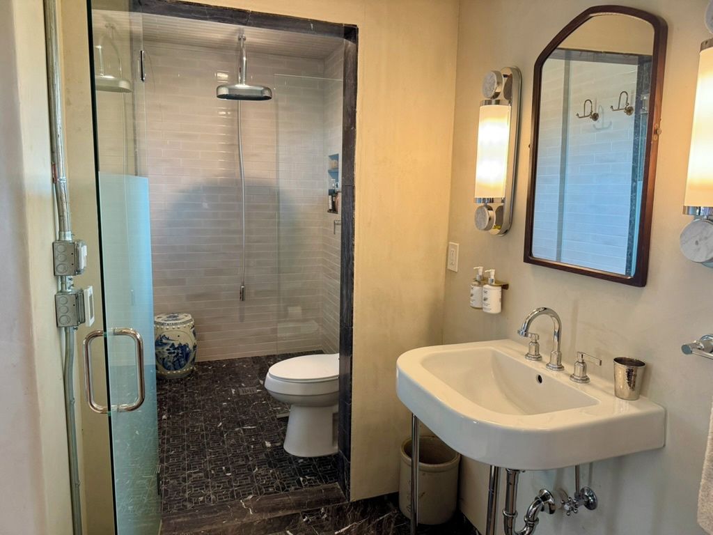 Une salle de bain avec une douche à parois de verre, un lavabo blanc et un miroir.