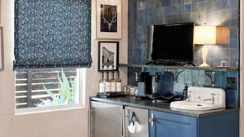 A compact kitchen with a window, a sink, a stove, and a television.