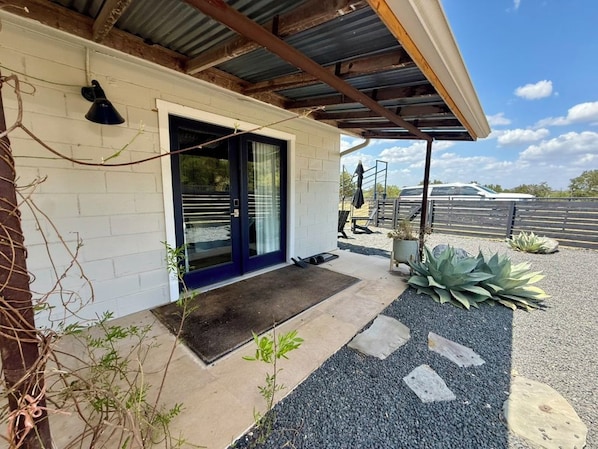 A building with a white exterior, a dark blue door, and a covered porch area.