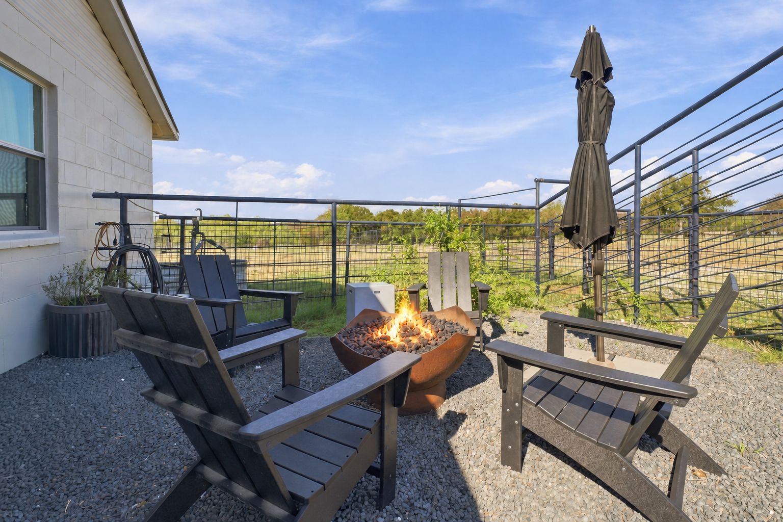 An outdoor seating area with a fire pit, chairs, and an umbrella.