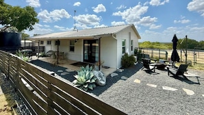 Ein modernes Haus mit einer Terrassenfläche, Sitzgelegenheiten im Freien und Blick auf die Landschaft.