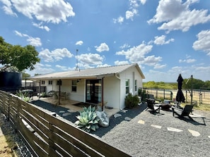 Ein modernes Haus mit einer Terrassenfläche, Sitzgelegenheiten im Freien und Blick auf die Landschaft.