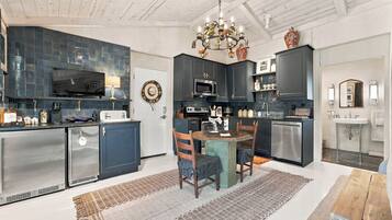 A modern kitchen with dark cabinetry, a dining area with a wooden table and chairs, and a chandelier.