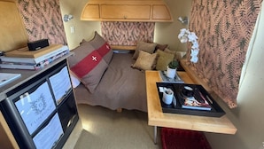 Ein kompaktes Wohnmobil-Interieur mit einem Bett, einem kleinen Tisch und einer Küchenzeile.