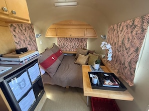 Ein kompaktes Wohnmobil-Interieur mit einem Bett, einem kleinen Tisch und einer Küchenzeile.