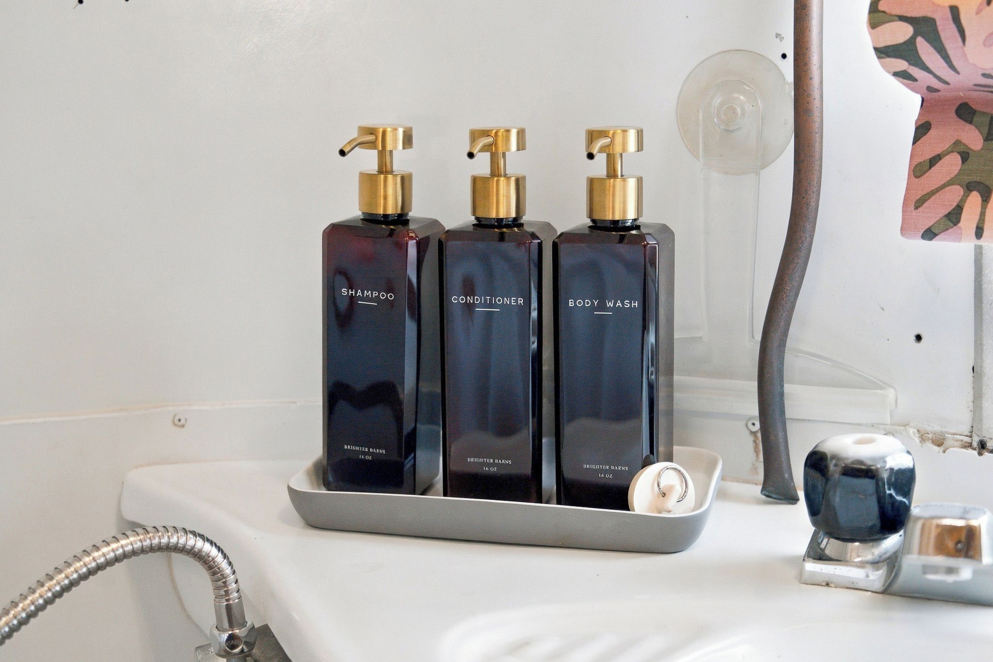 Three bottles of Brightner Balm products on a bathroom counter.
