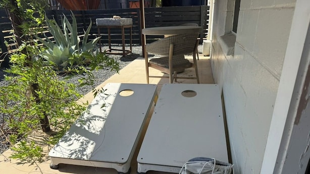 A patio area with a white wall, a small table, and a chair.