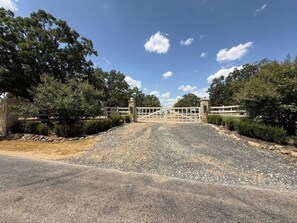 A entrada com portão leva a um edifício com uma parede de pedra de um lado e um portão de metal.