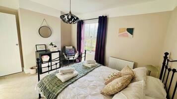 A bedroom with a bed, bedside table, chair, and a window with curtains.