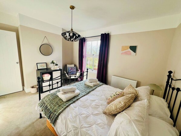 Una camera da letto con un letto, un comodino, una sedia e una finestra con tende.