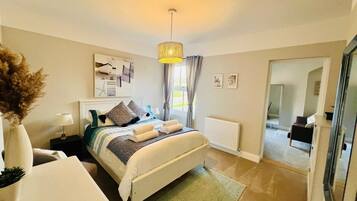 A hotel room with a bed, bedside table, lamp, and a view of the hallway.