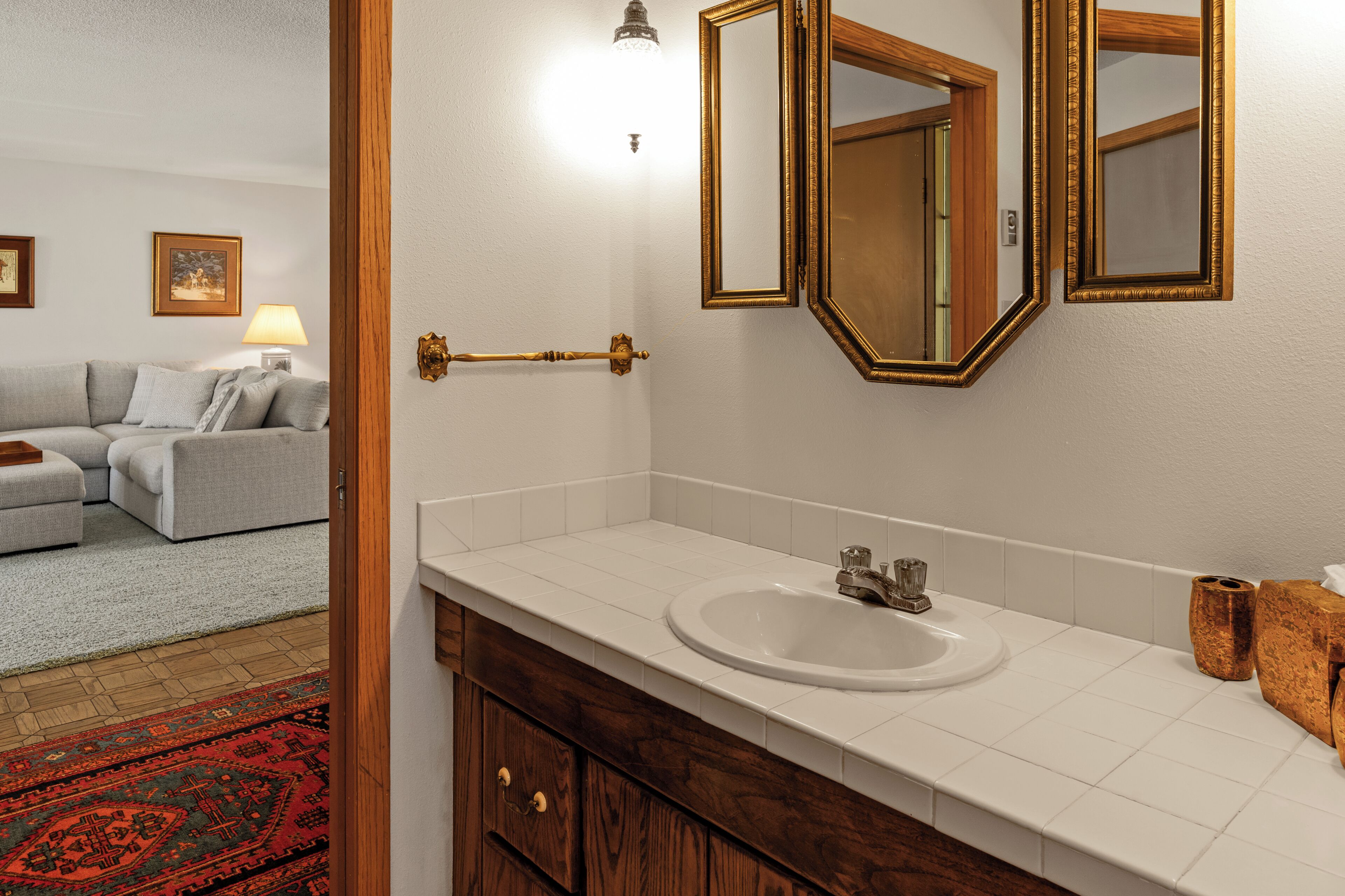 A bathroom with a white sink, wooden cabinet, and a large mirror.