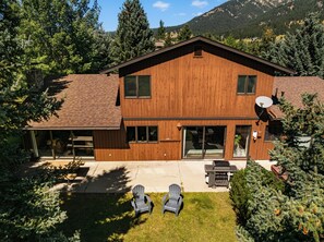 A two-story wooden house with a covered patio, a satellite dish, and a barbecue grill. - Charming 5-bedroom house in wonderful Big Sky for your getaway (Big Sky)