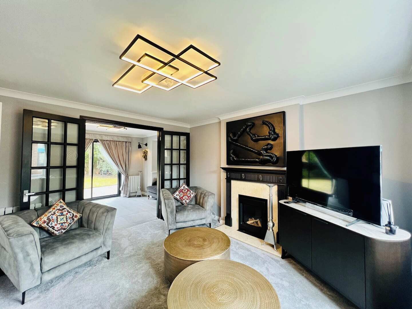 Un salon moderne avec une cheminée, un téléviseur et une grande fenêtre.