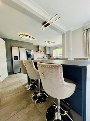 A modern kitchen with a central island, bar stools, and built-in appliances. - Boutique Home & Private Garden | City Escape (Colchester)
