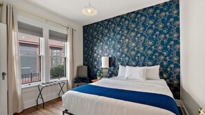 Une chambre à coucher avec un lit, une table de chevet, une lampe et une fenêtre avec des rideaux.