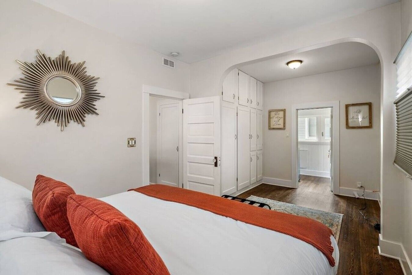 Une chambre à coucher avec un lit, un miroir et un couloir menant à une porte.