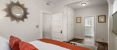 Une chambre à coucher avec un lit, un miroir et un couloir menant à une porte.