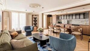 Uma sala de estar moderna com um sofá, poltronas, uma mesa de centro e um espaço de jantar com cadeiras e uma mesa.