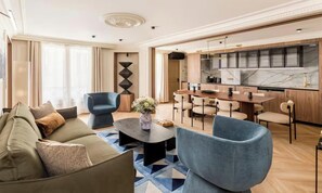Una sala moderna con sofá, sillones, una mesa de centro y una zona de comedor con sillas y una mesa.