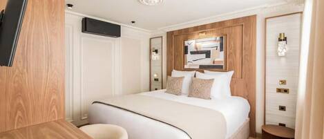 Una habitación de hotel con cama, escritorio, silla, televisor y espejo.