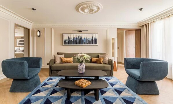 Una sala moderna con un sofá, dos sillones, una mesa de centro y una alfombra estampada.