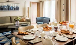 Un comedor con una mesa dispuesta para el desayuno, incluyendo platos, tazas y una tetera.