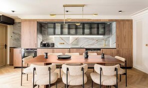A modern kitchen with a marble backsplash, wooden cabinets, and a dining area with a wooden table and chairs. - AN IDEAL SETTING FOR EXPERIENCING PARIS IN COMFORT AND STYLE NEAR OPERA (Paris)