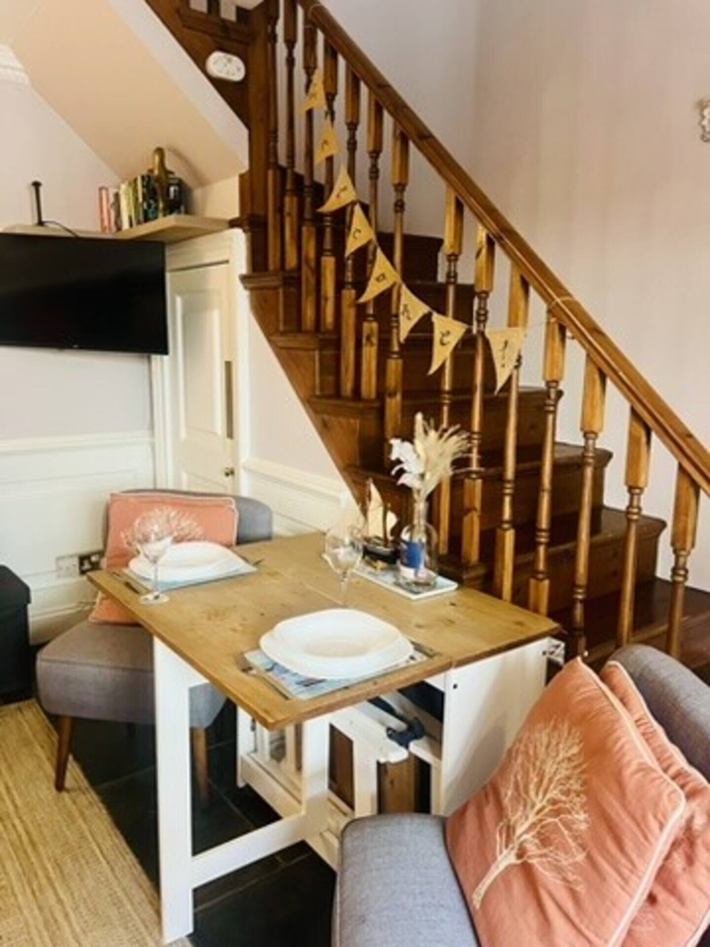 Ein Essbereich mit Holztisch, Stühlen und einer Treppe mit Holzwandungen.