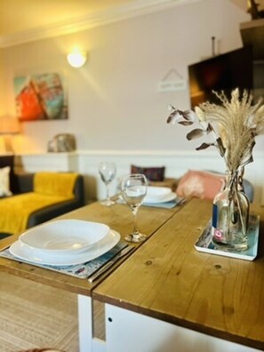 A dining table set with plates, cutlery, and a glass, with a decorative vase on a coaster.