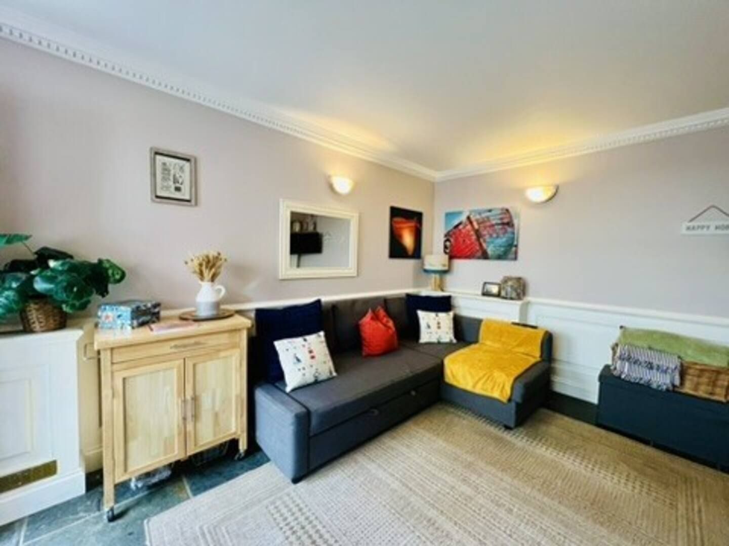 Een woonkamer met een bank, een bijzettafeltje en een kast.