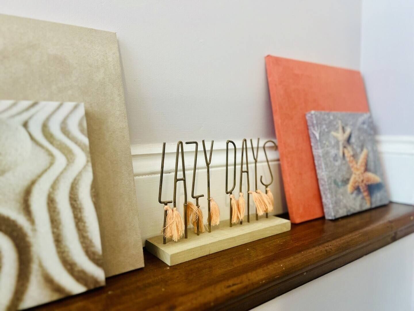 A shelf with decorative items including a sign that reads 'LAZY DAYS' and a framed picture with a starfish.