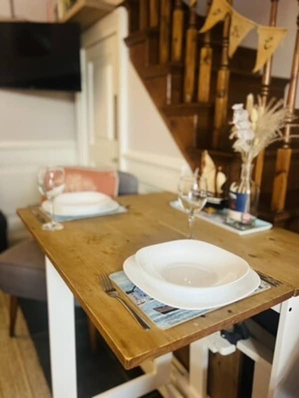 Een eettafel met een wit bord, een wijnglas en een kleine vaas met gedroogde planten.