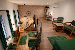 Ein modernes Interieur mit Treppe, Holzboden, grünen Polstersesseln und einer Ziegelwand.