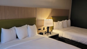 A hotel room with two beds, a nightstand with a lamp, and a wooden headboard. - IHV-A Country Living (Canton)