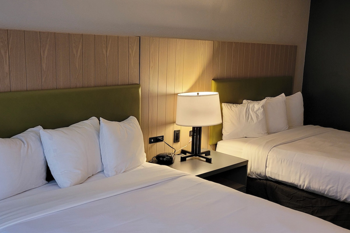 Ein Hotelzimmer mit zwei Betten, einem Nachttisch mit Lampe und einem Holzkopfende.