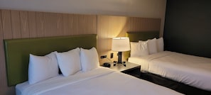Ein Hotelzimmer mit zwei Betten, einem Nachttisch mit Lampe und einem Holzkopfende.